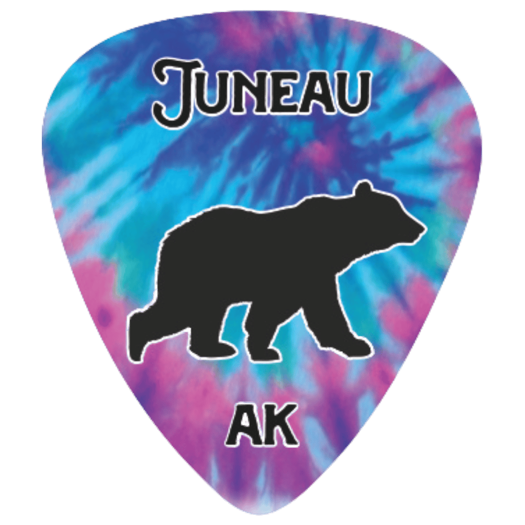 A guitar pick featuring a blue and purple tie-dye pattern with a black bear silhouette in the center, the word 'JUNEAU' at the top, and 'AK' at the bottom.