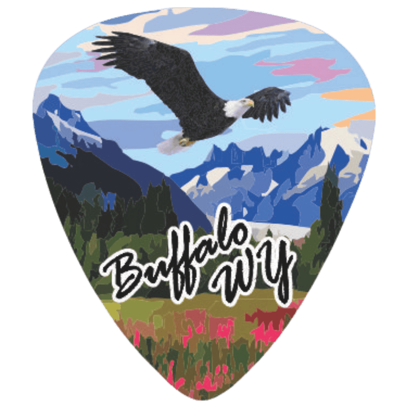 A guitar pick shaped graphic featuring a scenic Buffalo, Wyoming landscape with a bald eagle flying over mountains, trees, and wildflowers. The text 'Buffalo WY' is written across the lower center in white script with a black outline.