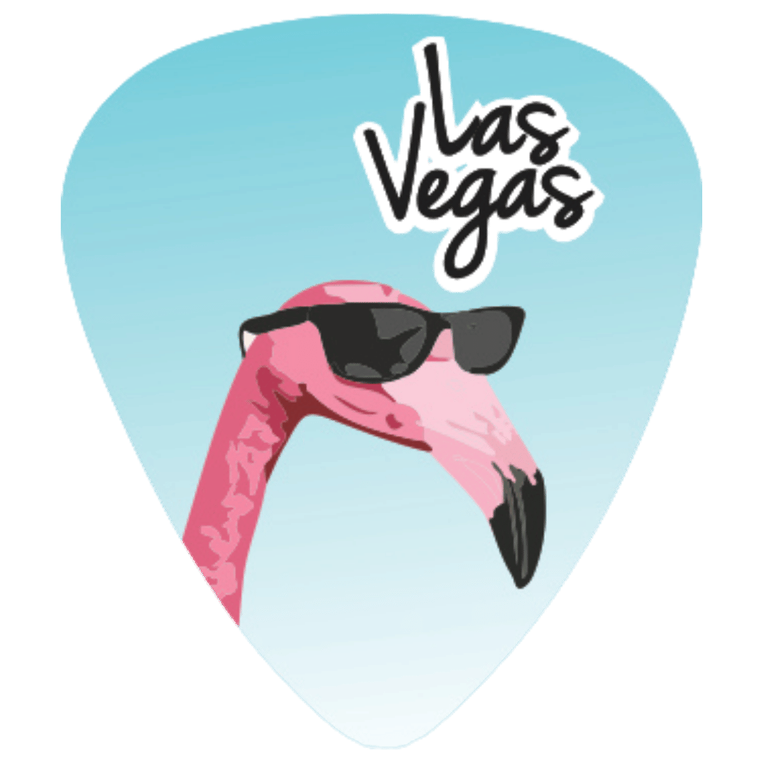 A guitar pick featuring a pink flamingo wearing black sunglasses against a light blue gradient background, with the words 'Las Vegas' in black script and white outline near the top.