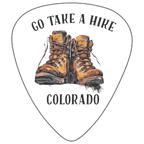 A white guitar-pick-shaped graphic with the words “GO TAKE A HIRE” at the top and “COLORADO” at the bottom, centered around an illustration of a pair of brown hiking boots. The design appears to be the product artwork itself rather than a lifestyle scene or auxiliary chart.