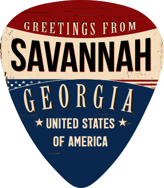 A guitar-pick-shaped sign or sticker with a distressed patriotic design reading 'Greetings from Savannah, Georgia, United States of America' in cream lettering on red, beige, and dark blue sections.